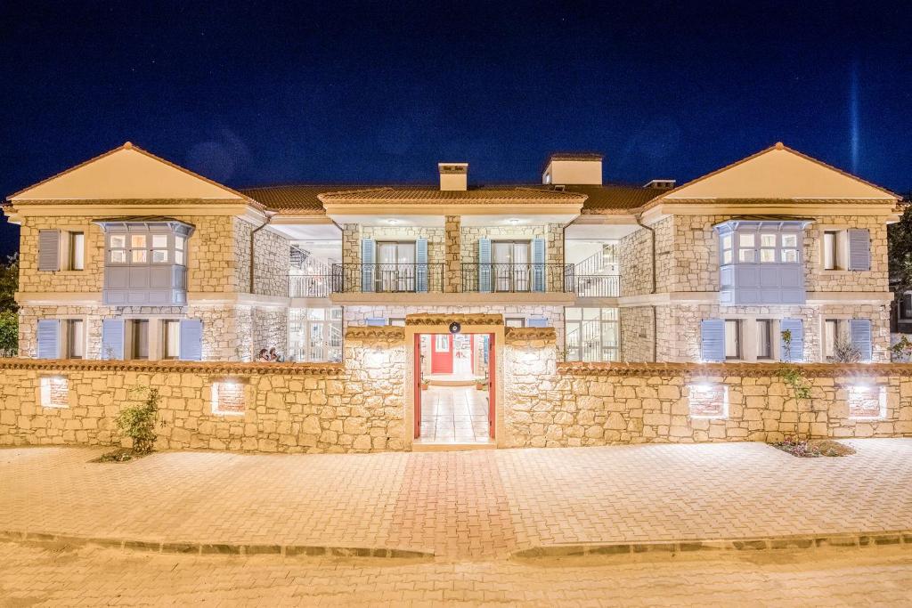 una grande casa in pietra con una porta rossa di Bademli Konak Otel a Datça