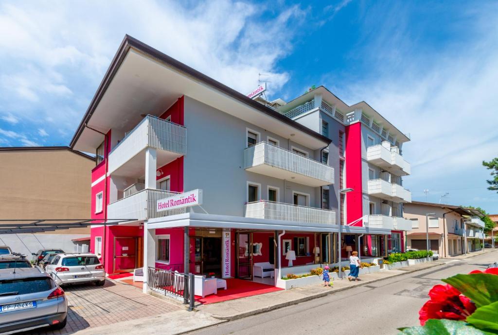 un edificio rojo y blanco en una calle en Hotel Romantik en Lignano Sabbiadoro