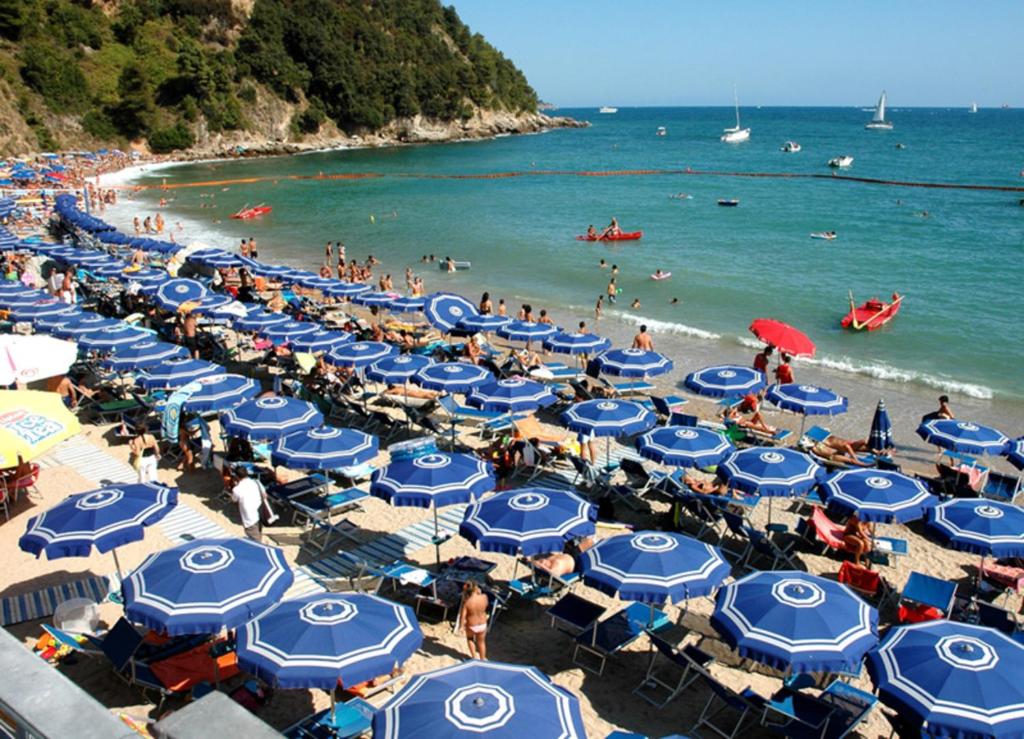 レーリチにあるAppartamento di Franco Baia Bluの青白の傘と水中の人々を持つビーチ