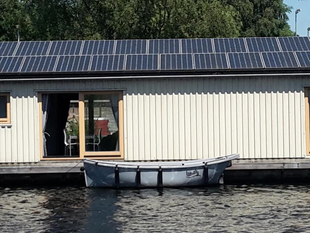 ein Boot auf dem Wasser neben einem Haus mit Sonnenkollektoren in der Unterkunft Boathouse Amsterdam in Amsterdam