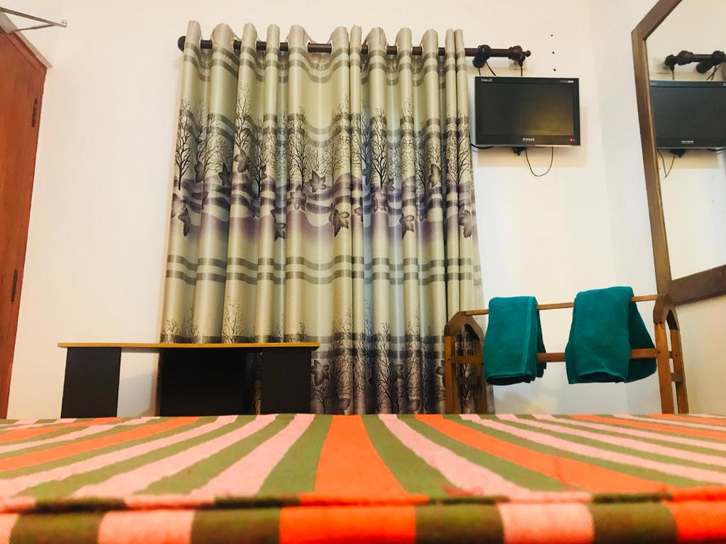 a bedroom with a bed and a curtain and a tv at Princely House Apartment in Galle