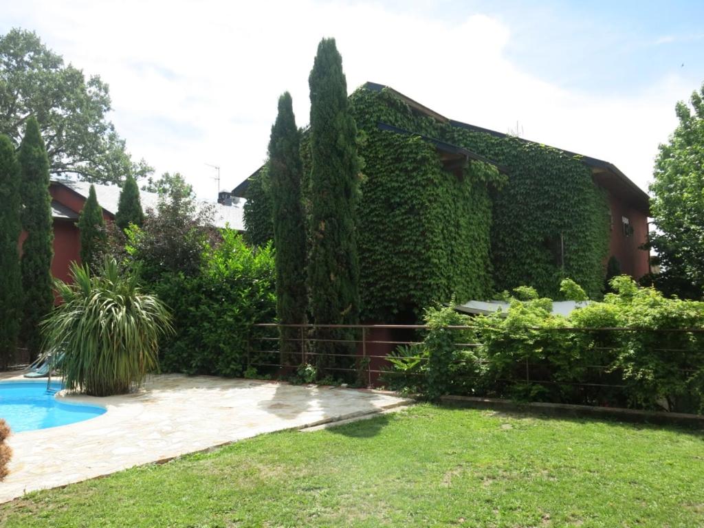 a house covered in ivy with a swimming pool at Chalet Navacerrada Piscina Privada in Navacerrada