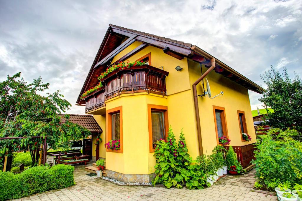 uma casa amarela com varanda e flores em Penzión Janega em Liptovský Mikuláš