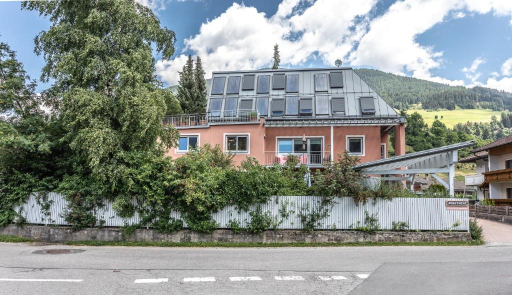 a pink house behind a white fence with a tree at Apartment Hochpustertal in Heinfels