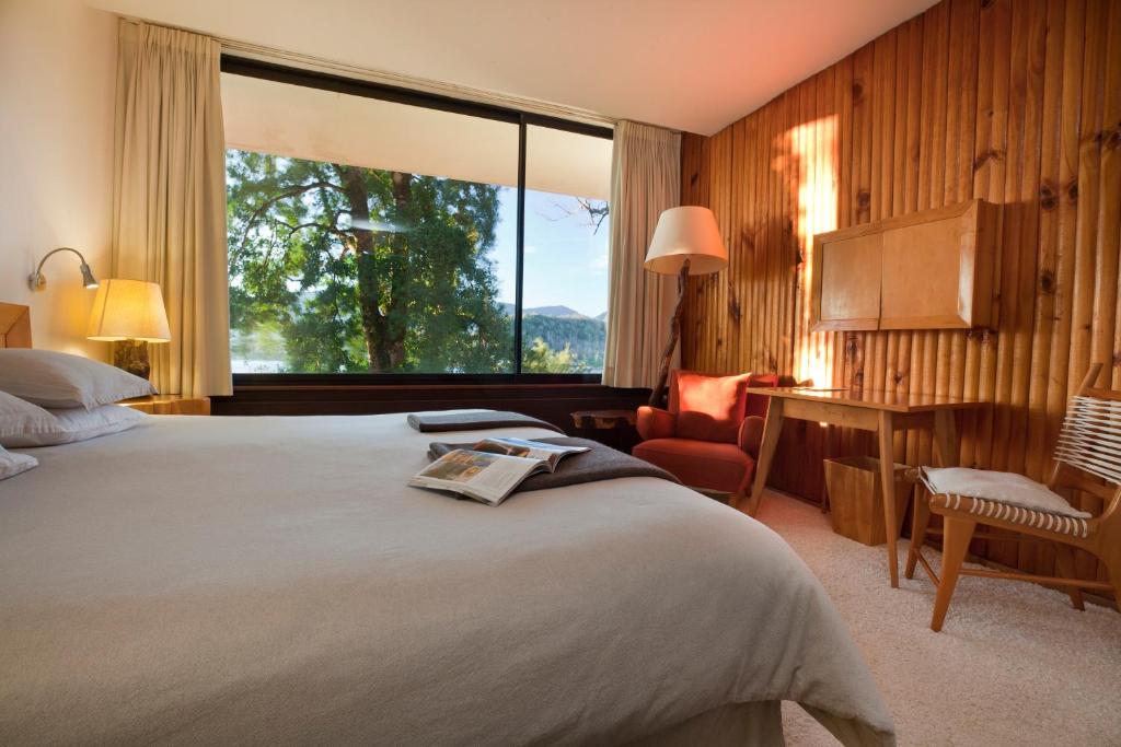 um quarto de hotel com uma cama e uma janela grande em Hotel Antumalal em Pucón