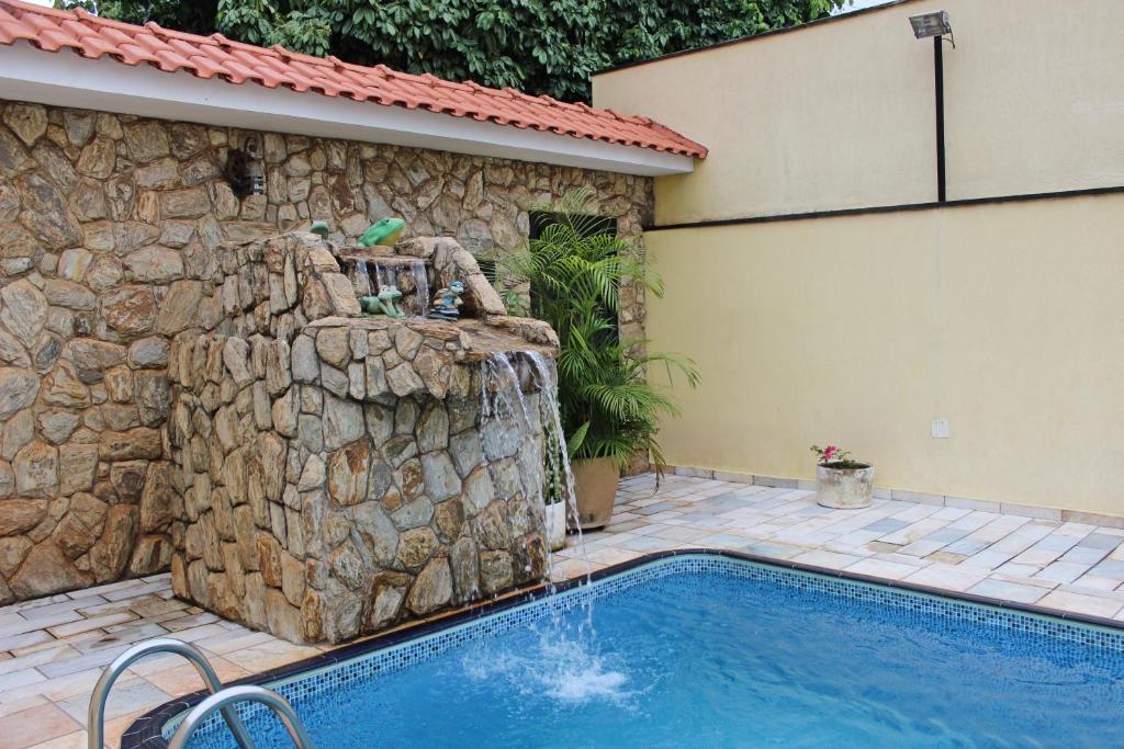 uma piscina com uma parede de pedra ao lado de uma casa em Pousada Acolhedora em Ribeirão Preto