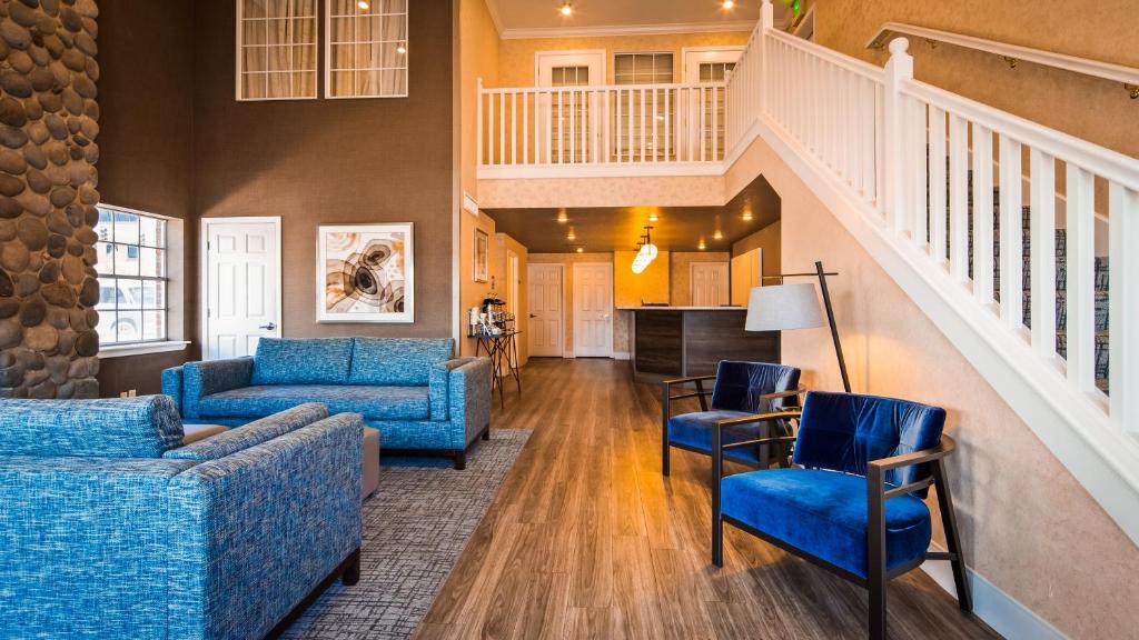 a living room with blue furniture and a staircase at Best Western Horizon Inn in Medford