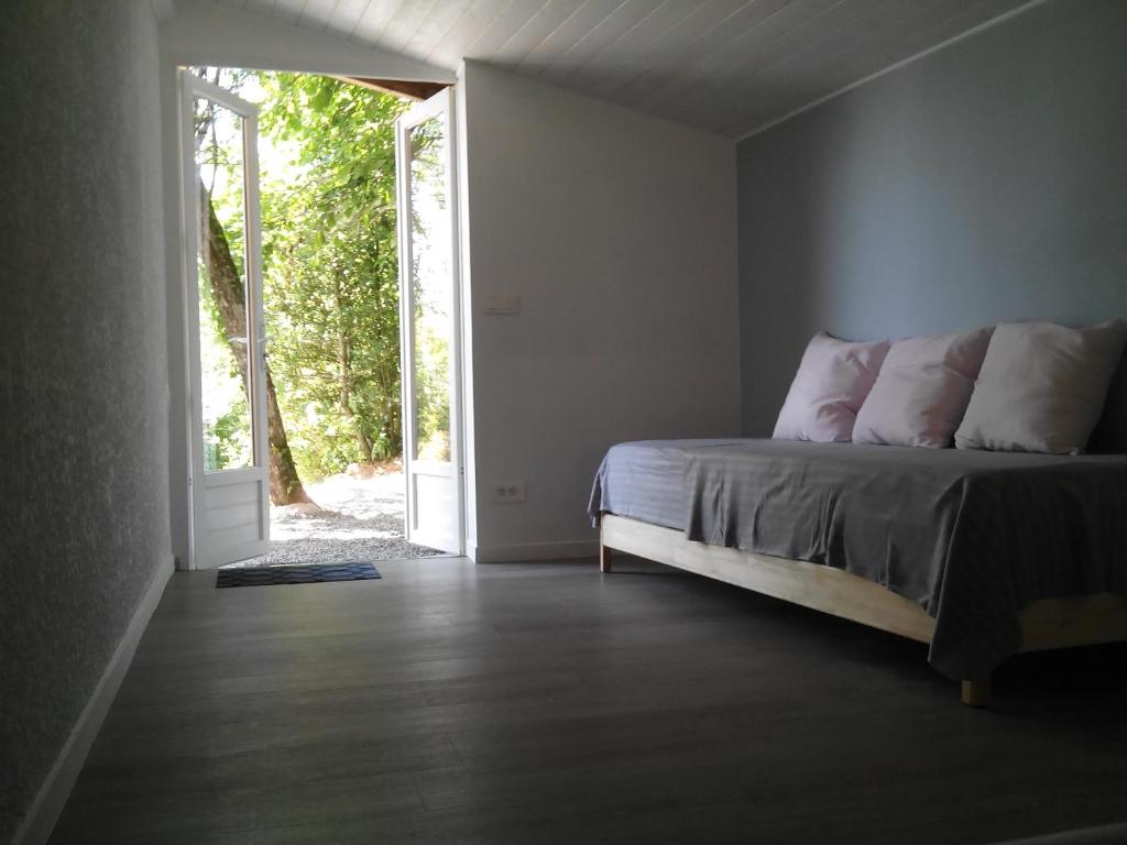 a bedroom with a bed and an open door at Le Jardin Ombragé in Saint-Paul-dʼIzeaux