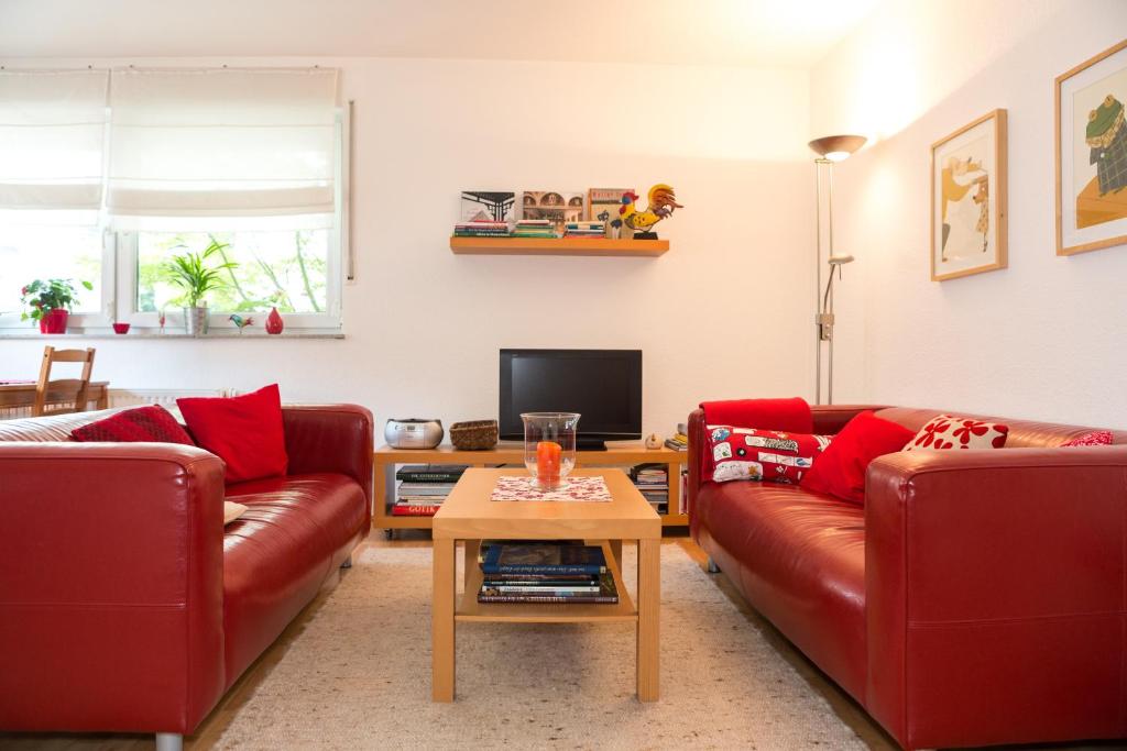 una sala de estar con 2 sofás rojos y una mesa. en Ferienwohnung Mittendrin, en Bergisch Gladbach