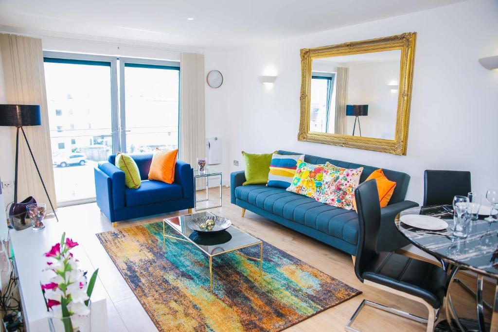 een woonkamer met een blauwe bank en een spiegel bij RIVERSIDE 2 BED APARTMENT in North Woolwich
