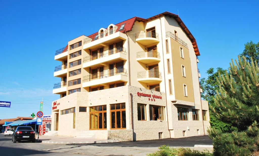 ein hohes Gebäude mit einem davor geparkt in der Unterkunft Hotel Victoria in Costinești