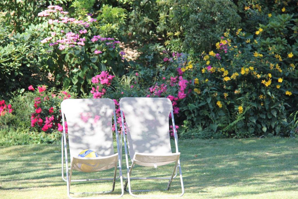 two chairs sitting in front of a garden with flowers at La Villa Blanche in Bussy-Saint-Martin