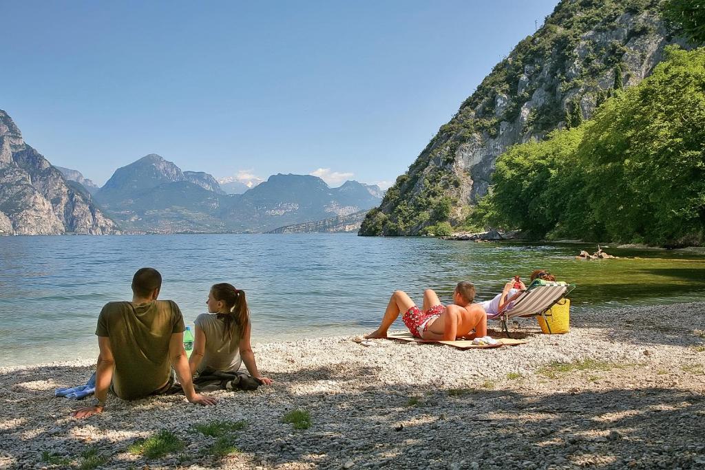 eine Gruppe von Menschen, die am Ufer eines Sees sitzen in der Unterkunft Hotel Baitone - Nature Village in Malcesine