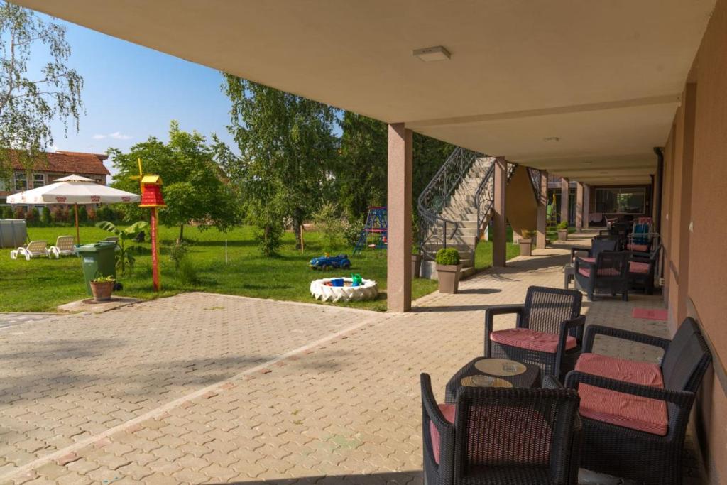 a patio with chairs and tables and an umbrella at Apartmani "ROSHU" in Soko Banja