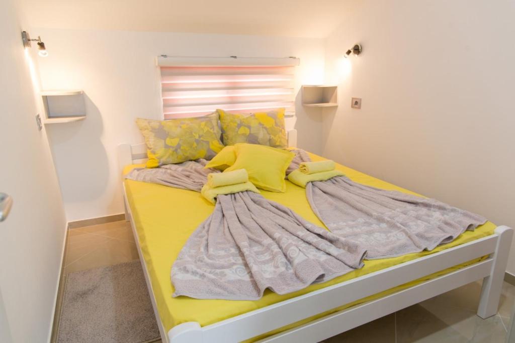 a bedroom with a yellow bed with a yellow blanket at Apartmani "ROSHU" in Soko Banja