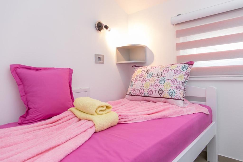 a bedroom with two beds with pink sheets and pillows at Apartmani "ROSHU" in Soko Banja