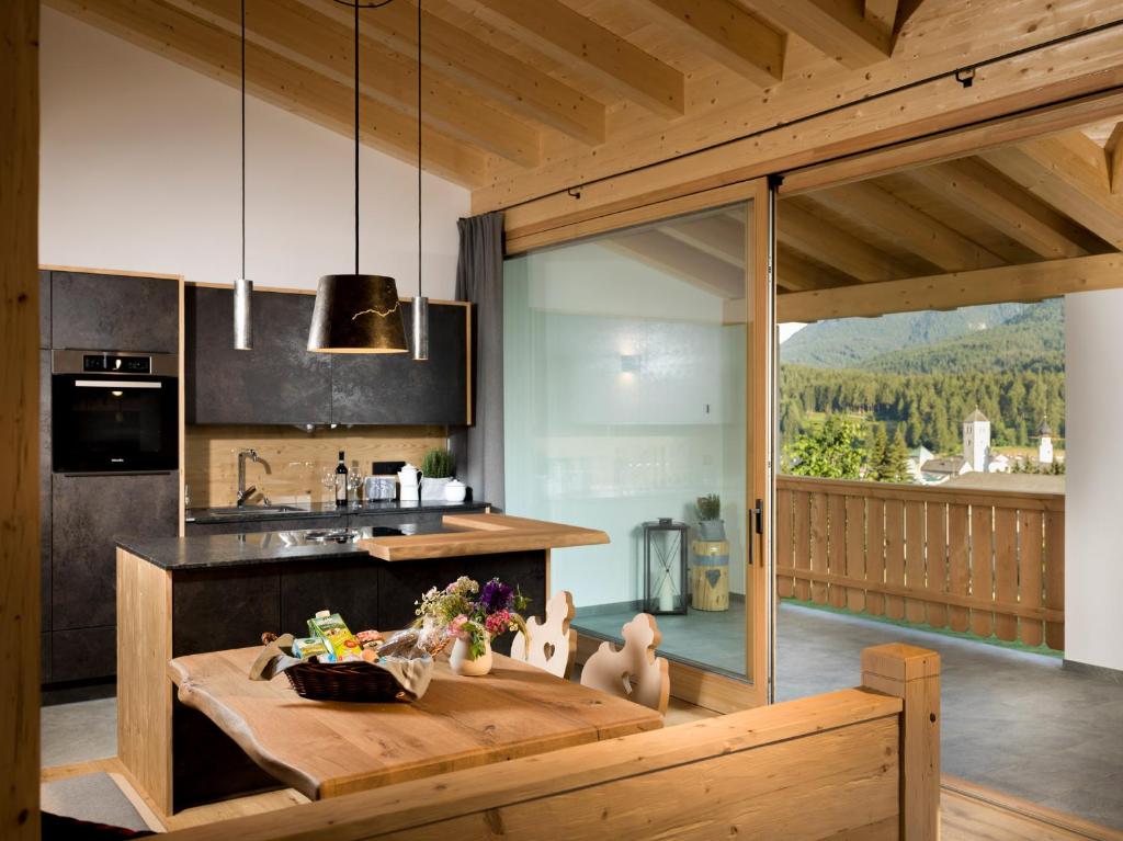 une cuisine avec une table en bois et une grande fenêtre dans l'établissement Chalet Novalis, à San Candido