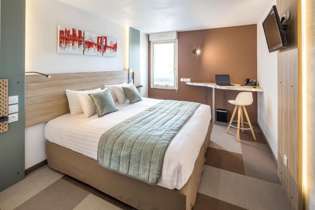 een hotelkamer met een bed en een bureau bij Carré Pau Airport Hôtel in Serres-Castet