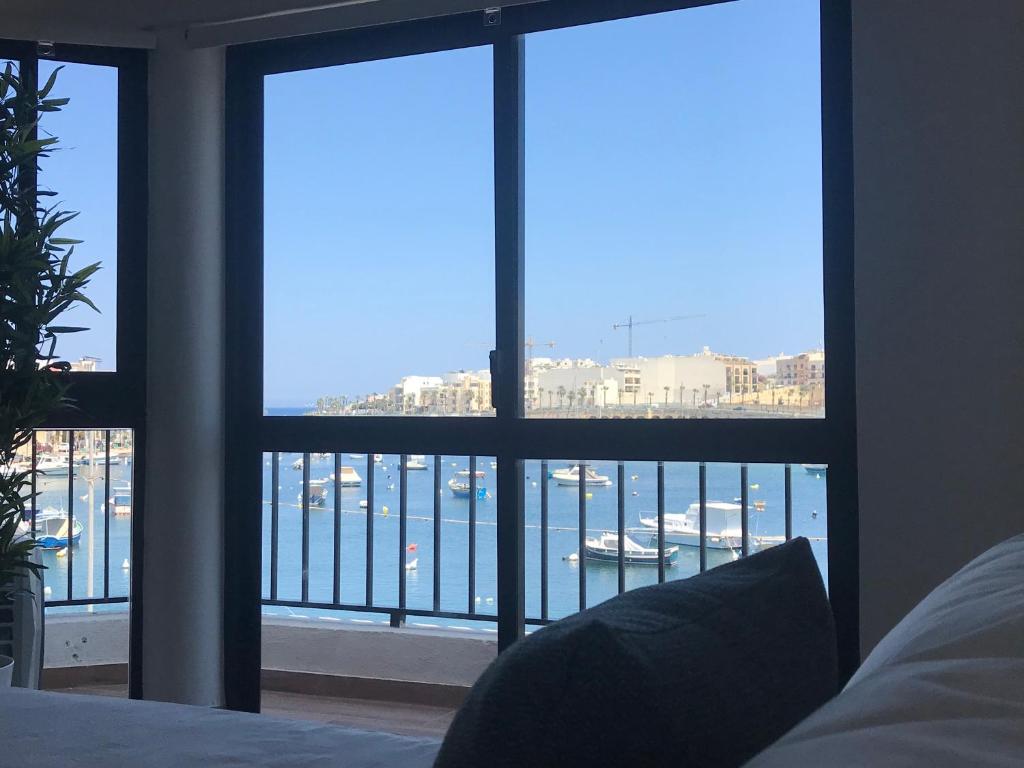 a bedroom with a large window with a view of a harbor at Sunrise Creek in Marsaskala