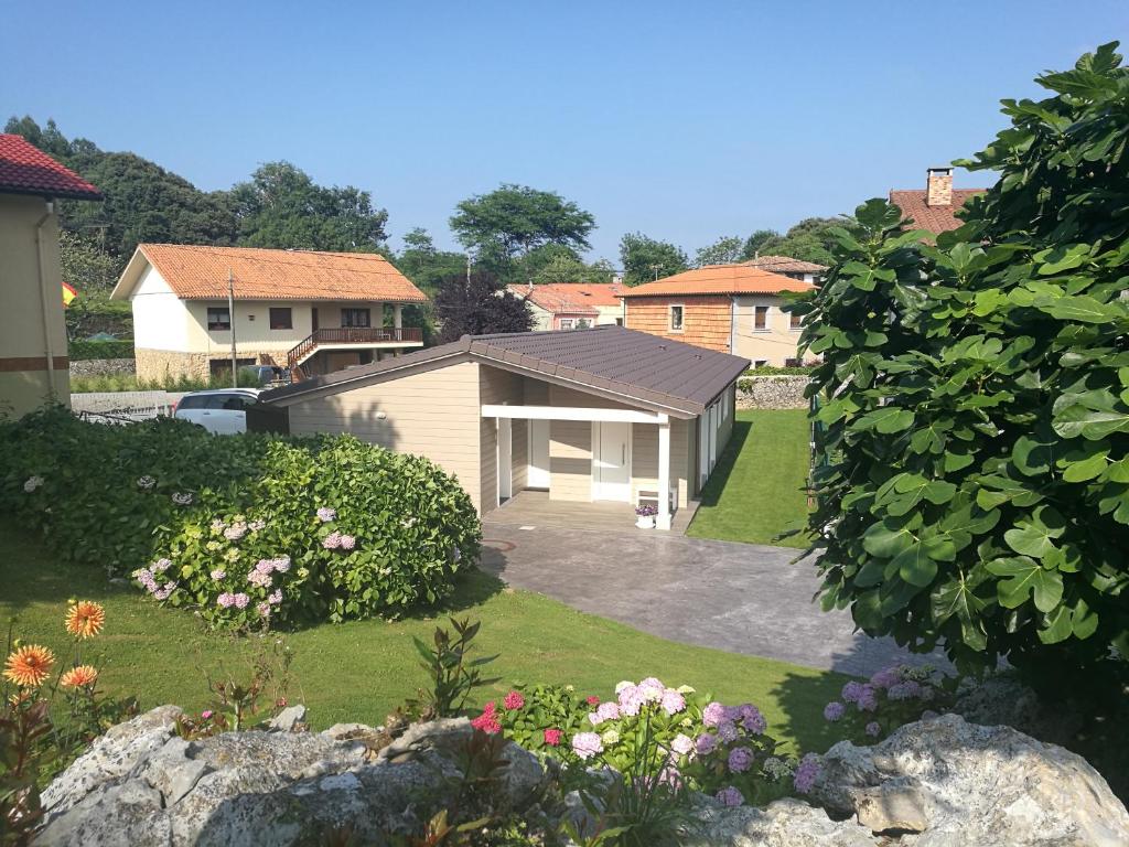 a house with a garage in a yard with flowers at Apartamentos La Encina in Celorio