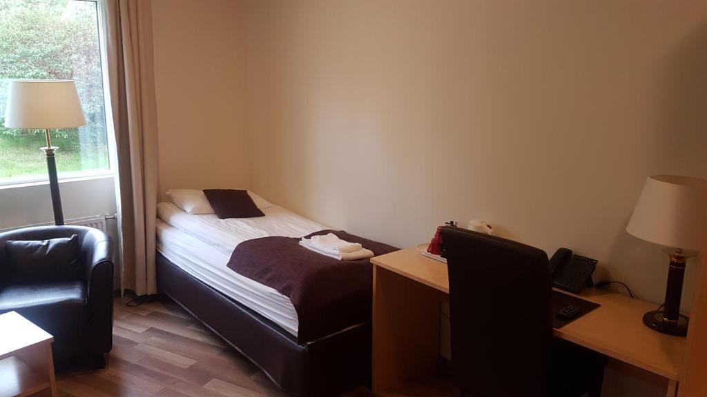 a small bedroom with a bed and a desk and a window at Hotel Hallormsstadur in Hallormsstaður