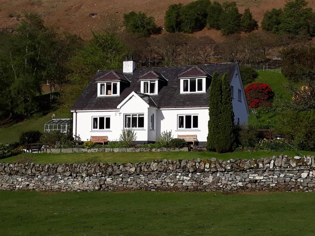 a large white house with a stone wall at Clachan Farmhouse B & B in Ullapool