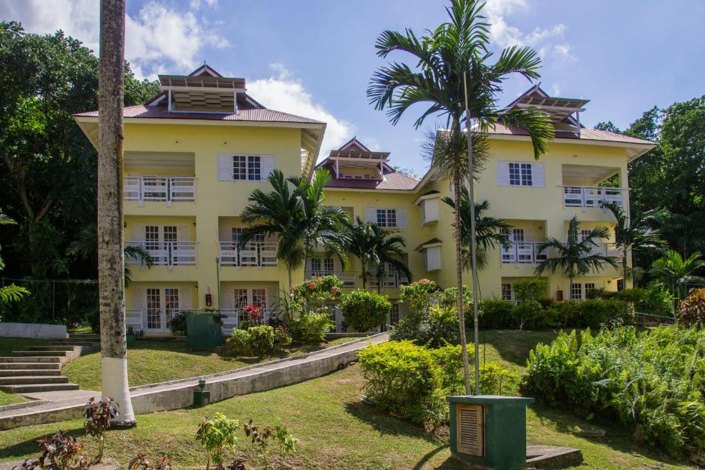 a large yellow building with palm trees in front of it at Hillview At Mystic Ridge in Ocho Rios