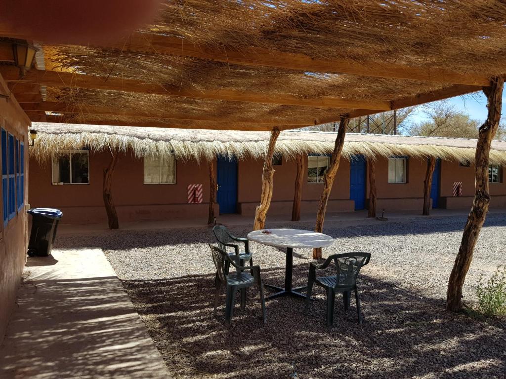 een tafel en stoelen onder een rieten dak bij Andes Nomads Desert Camp & Lodge in San Pedro de Atacama