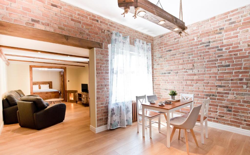 uma parede de tijolos numa sala de estar com uma mesa e cadeiras em Apartament Starówka 2 em Toruń