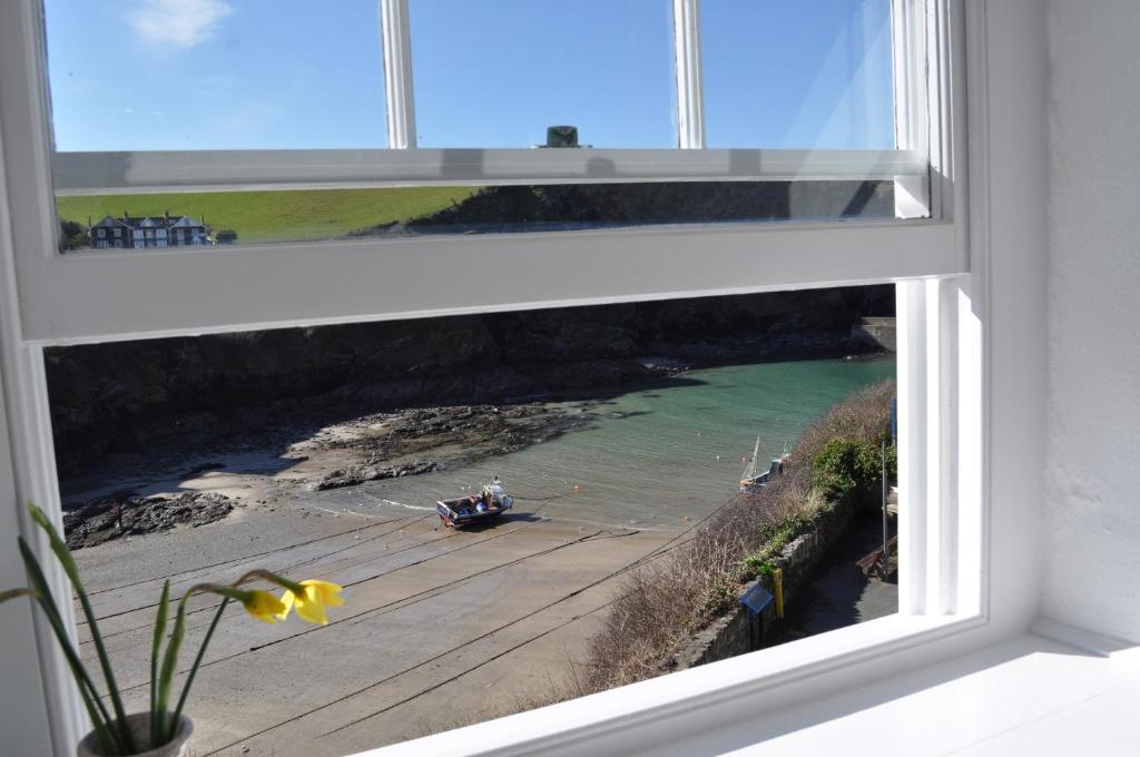 a window with a view of a boat in the water at The Gallery in Port Isaac