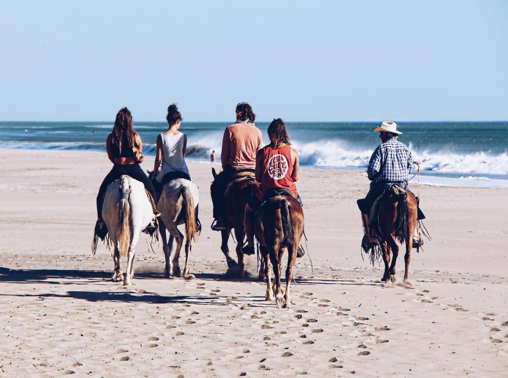 a group of people riding horses on the beach at Casitas Pacific in Popoyo