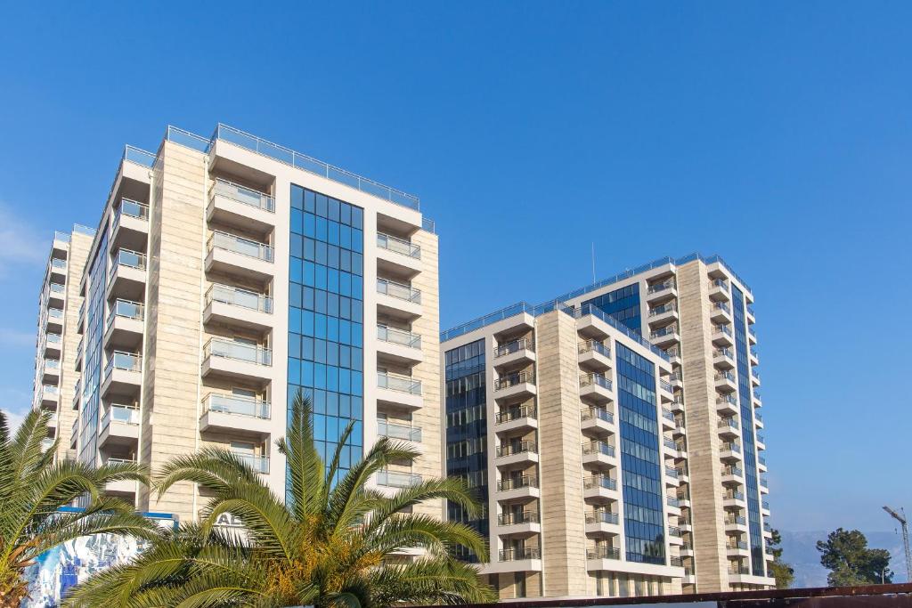 two tall buildings with palm trees in front of them at Mateja&Fontana Apartment in Budva