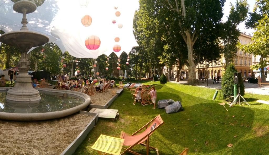 um parque com pessoas sentadas em cadeiras em torno de uma fonte em Apartment Zrinjevac em Zagreb