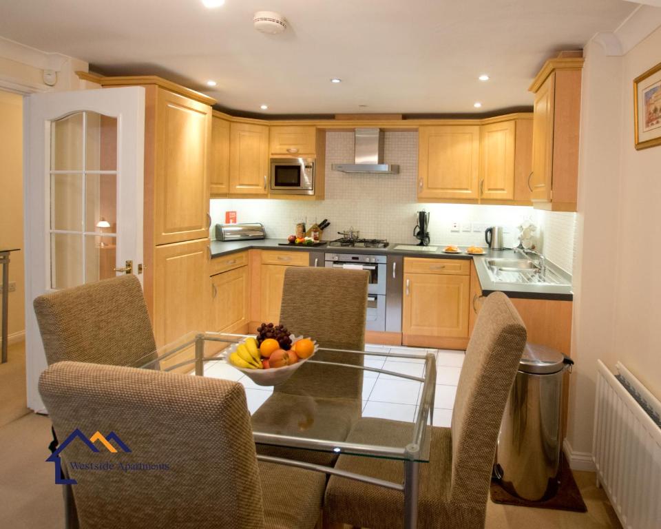 a kitchen with a glass table with chairs and a bowl of fruit at Bounty Suite Basingstoke in Basingstoke