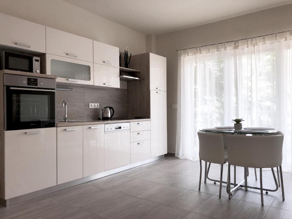 uma cozinha com armários brancos e uma mesa com cadeiras em Exclusive Home em Pécs