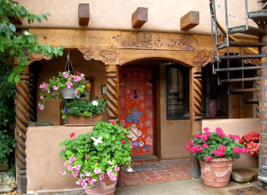 a house with pots of flowers in front of a door at La Dona Luz Inn an Historic B&B in Taos