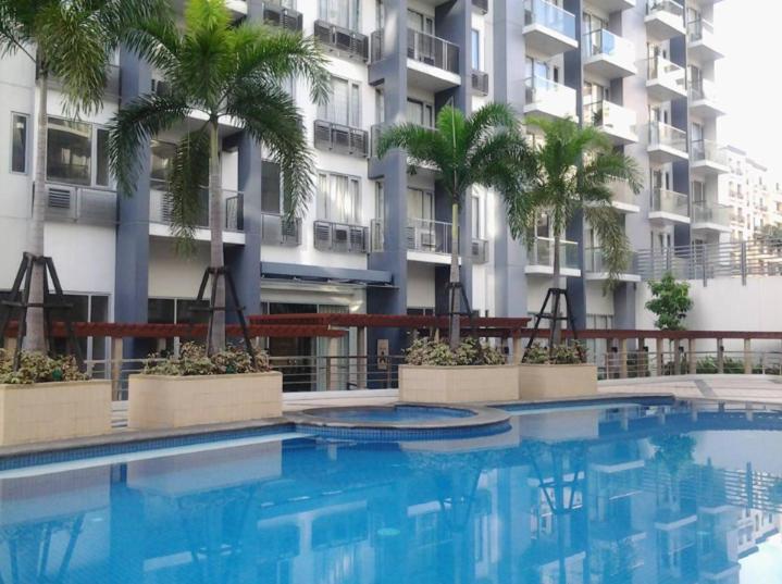 a swimming pool in front of a building with palm trees at One Palm Tree Villas close to Manila Airport - Terminal 3 in Manila
