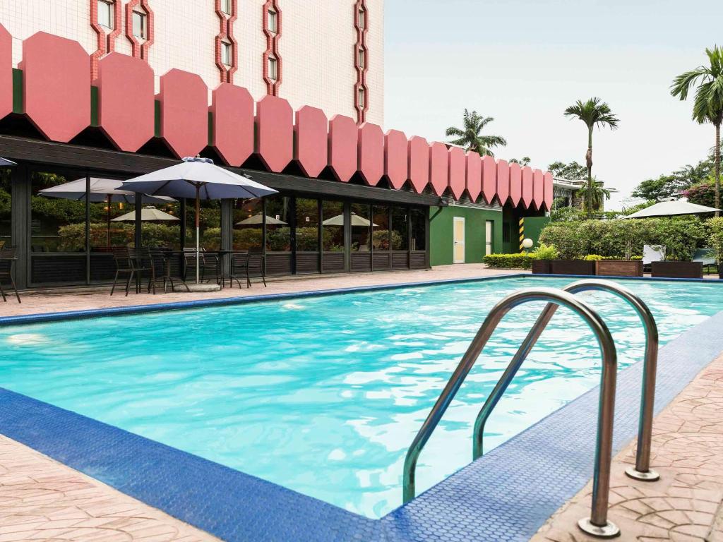 - une piscine avec un parasol dans l'établissement ibis Douala, à Douala