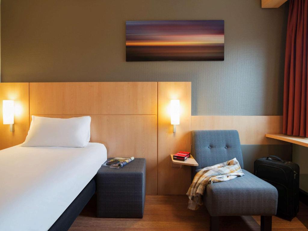 a hotel room with a bed and a chair at ibis Rotterdam Vlaardingen in Vlaardingen