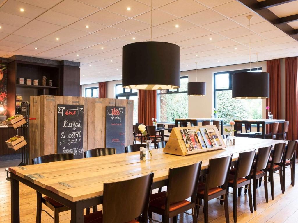 a dining room with a large wooden table and chairs at ibis Rotterdam Vlaardingen in Vlaardingen