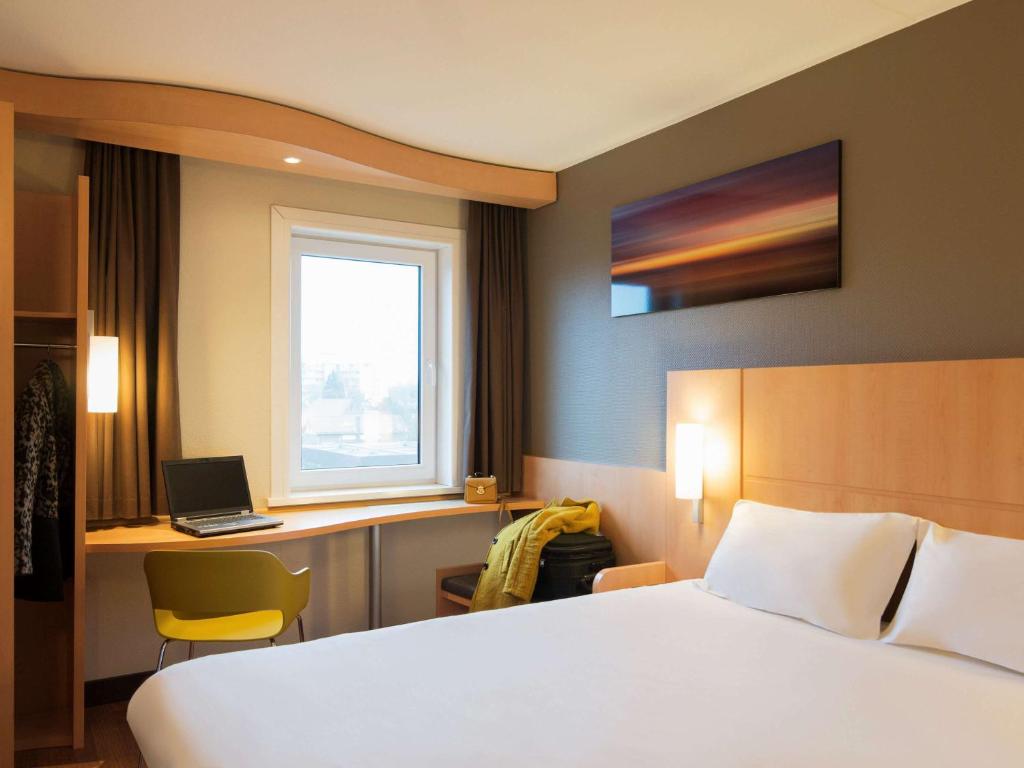 a bedroom with a bed and a desk with a laptop at ibis Rotterdam Vlaardingen in Vlaardingen