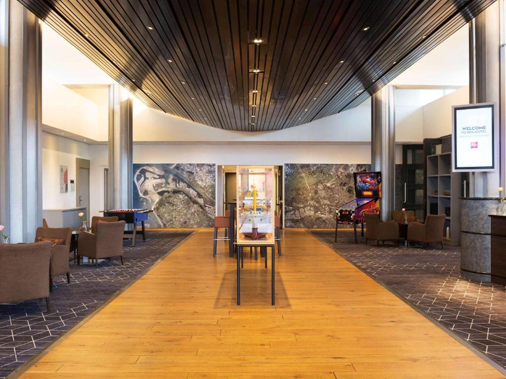 a lobby with tables and chairs in a building at ibis Rotterdam Vlaardingen in Vlaardingen