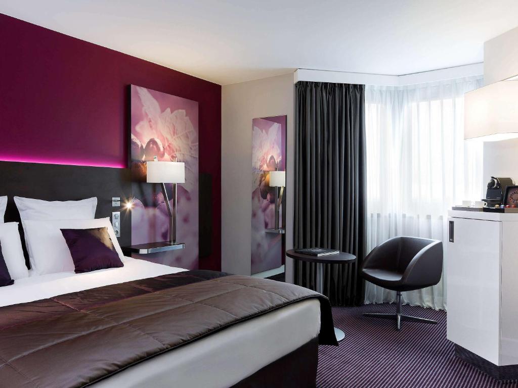 um quarto de hotel com uma cama e uma parede roxa em Mercure Reims Centre Cathédrale em Reims