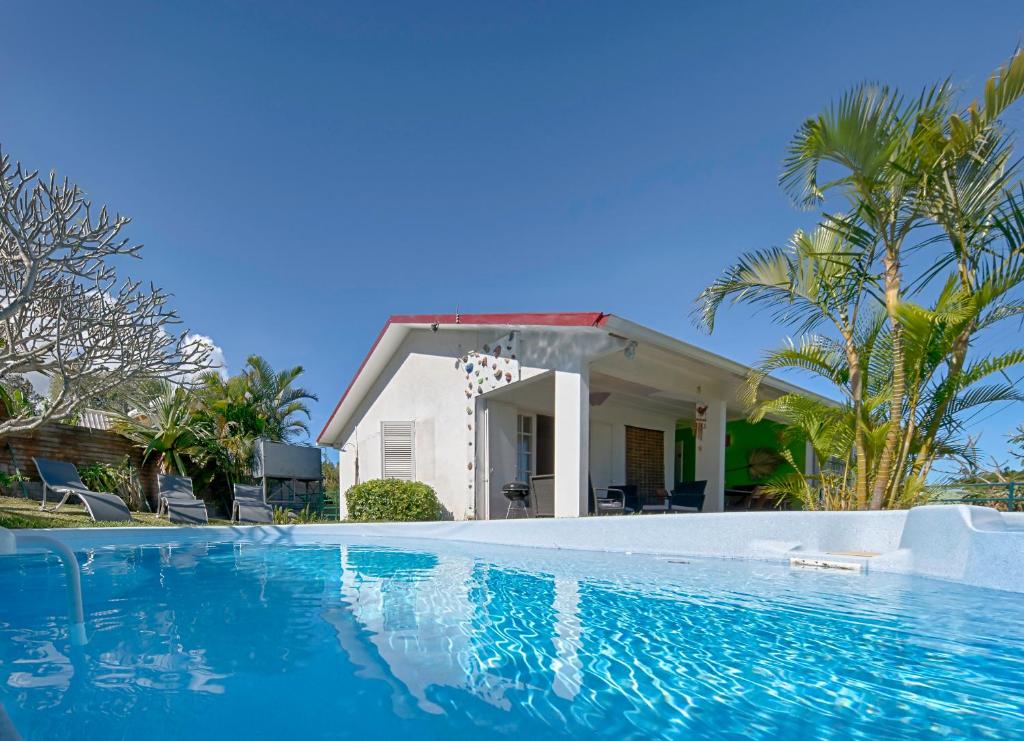 a villa with a swimming pool in front of a house at Villa Ti caz do miel avec piscine et bassin de détente à remous au Tampon pour 8 personnes in Le Tampon