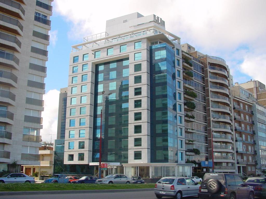 un edificio alto con coches estacionados frente a él en Cala di Volpe Boutique Hotel, en Montevideo