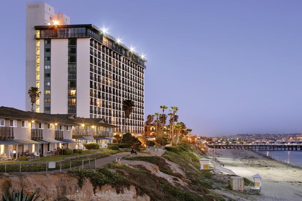 a building on the beach next to the ocean at night at Capri by the Sea by All Seasons Resort Lodging in San Diego