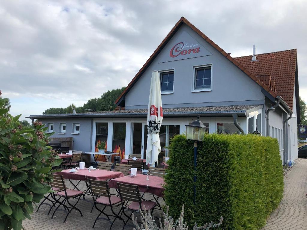 ein Restaurant mit Tischen und Stühlen vor einem Gebäude in der Unterkunft Pension Cora in Boltenhagen