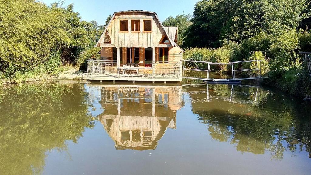 una casa seduta su un fiume con il suo riflesso nell'acqua di Cabanes de moon a Moon-sur-Elle