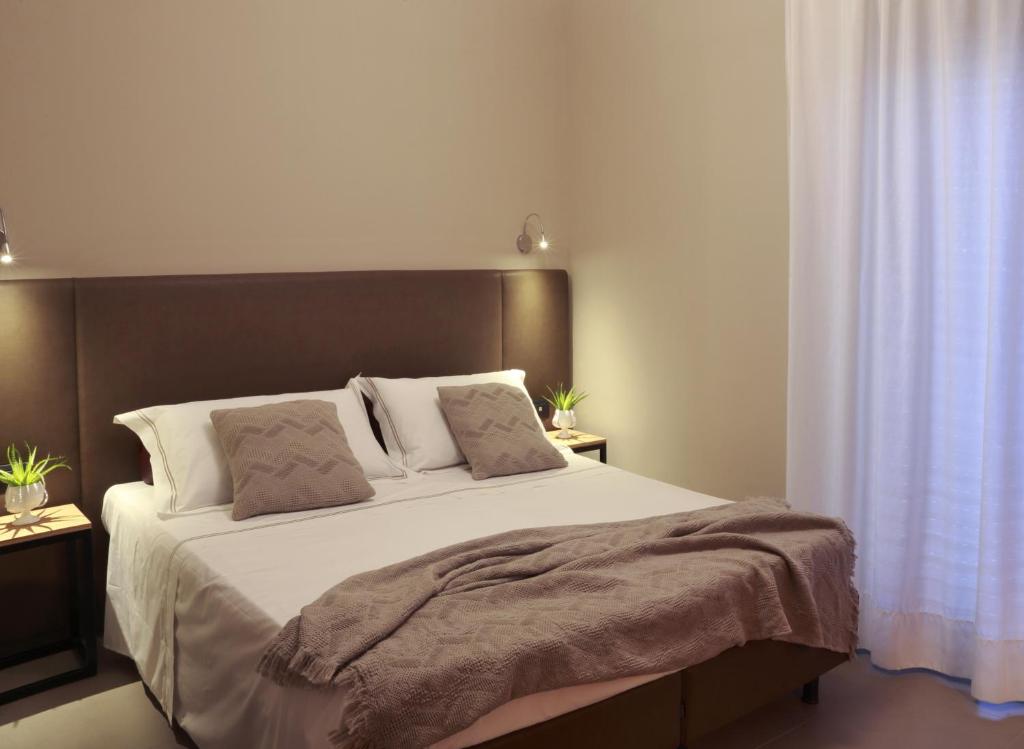 una camera da letto con un grande letto con lenzuola e cuscini bianchi di Hotel Aloisi a Lecce
