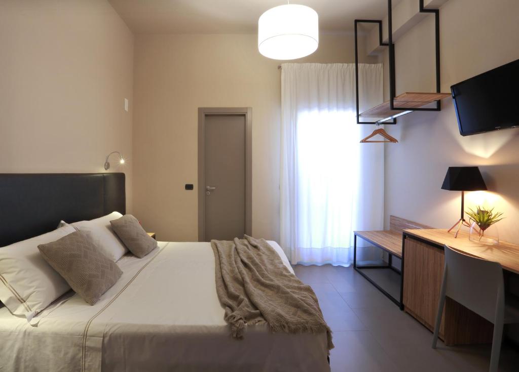 a bedroom with a bed and a desk and a window at Hotel Aloisi in Lecce